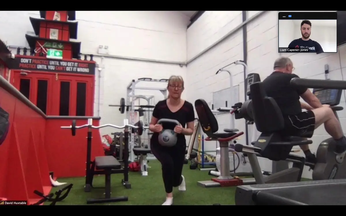 Lady doing front lunge with kettle bell in Gorseinon with personal trainer in Swansea