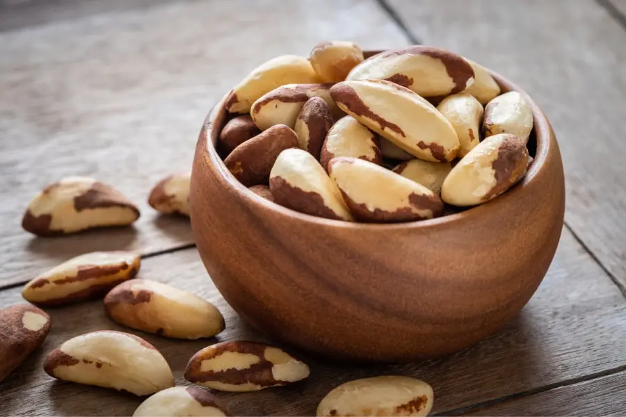 Mood Boosting foods Whole brazil nuts in wooden bowl with some loose brazil nuts scattered on the table