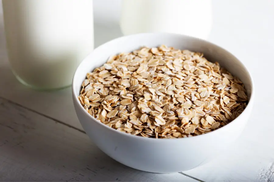 Mood Boosting foods a small white bowl full of oats with a close up of a pint of milk in the background