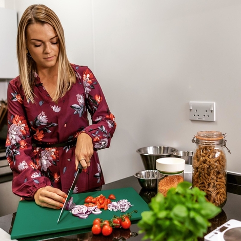 Hannah Baugh a nutritionist at Swansea Strength and Conditioning cutting up vegetables on a chopping board on a kitchen worktop