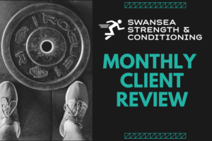 Weightlifter standing over weights plate to represent Monthly Client Review with personal trainers at Swansea Strength and Conditioning