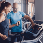 A personal trainer with a slender woman setting her up for a training session on the running machine as part of her training regime to lose weight